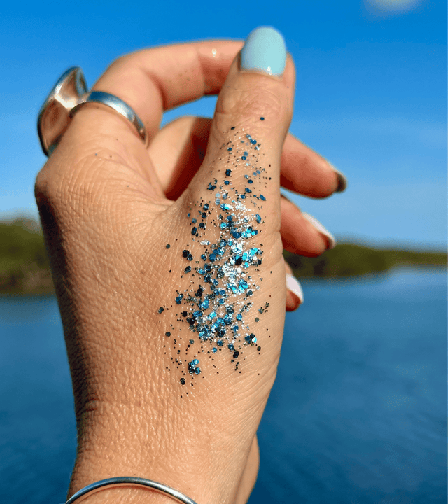 Deep Ocean Blue and Green Mix on the back of a hand over a beautiful body of water